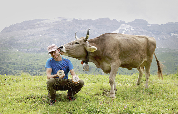 Reto Buchli, Initiant von Horn+Milch, lässt sich bei der Präsentation der neuen Mutschli von einer Hornkuh liebkosen. (ZVG)