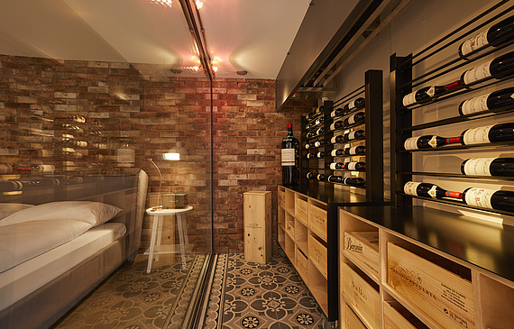 Vom klimatisierten Tresor für Rotweine schweift der Blick auf das Doppelbett. Auf dessen anderer Seite steht der ebenfalls begehbare Weisswein-Tresor. Beide sind gut bestückt und die Gäste dürfen sich bedienen. (Bild ZVG)